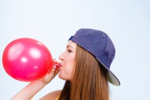 Teen girl blowing red balloon.