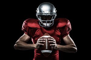 Composite image of american football player holding ball