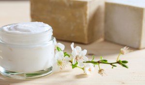 Moisturizing cream and almond blooms on wooden background