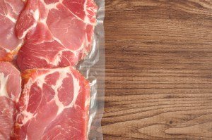 Vacuum packed meat displayed on a wooden background